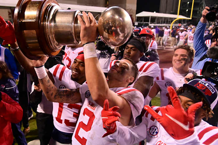 Nov 25, 2021; Starkville, Mississippi, USA; Mississippi Rebels quarterback Matt Corral (2) hoist the Egg Bowl trophy after the game against the Mississippi State Bulldogs at Davis Wade Stadium at Scott Field. Mandatory Credit: Matt Bush-USA TODAY Sports